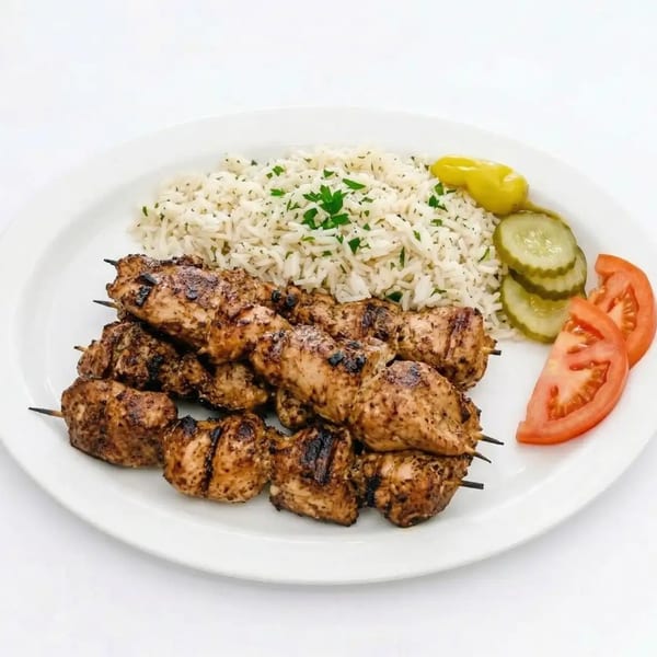 Grilled chicken skewers with rice, pickles, and tomato slices on a white plate.