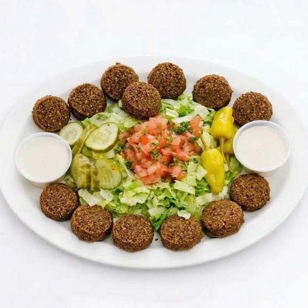 A platter of falafel, shredded lettuce, diced tomatoes, pickles, and two dipping sauces.