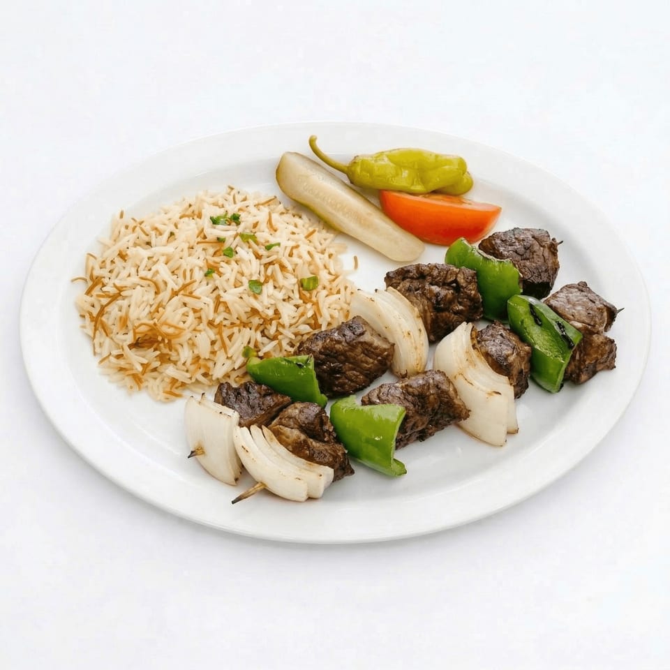 Beef shish kebab with rice, pickled cucumber, tomato, and green pepper on a white plate.